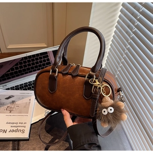 Close-up of vintage brown boston bag with dual zippers and fuzzy monster charm