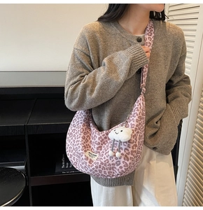 Detail of pink leopard print crescent bag with white cloud charm on casual model