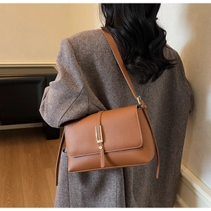 Detail of a brown lychee pattern leather underarm bag with gold metal buckle