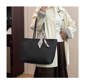 Close-up of black litchi grain tote bag with a decorative silk scarf on the handles