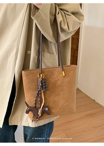 Detail of vintage brown suede tote bag featuring a cute dachshund charm and minimalist design
