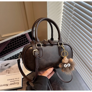 Detail of retro dark brown leather Boston bag with plush monster charm and gold hardware
