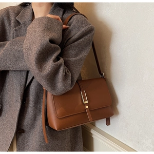 Close-up of brown lychee grain leather underarm bag with matte gold buckle detailing