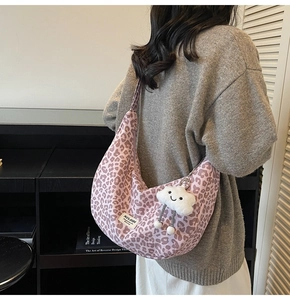 Pink leopard print crescent tote bag detail with white cloud plush charm and brand tag