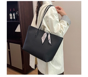 Detail of black lychee leather tote bag with a patterned silk scarf on the shoulder strap