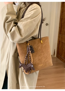 Brown suede tote bag with cute dachshund charm and chocolate pendant on model shoulder
