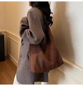 Detail of dark brown suede tote bag showing large capacity and soft texture on shoulder