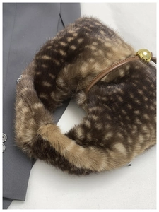 Detail of plush leopard print faux fur bag with gold spherical buckle and leather strap
