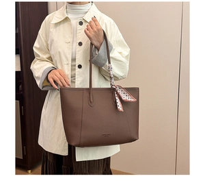 Detailed view of brown lychee leather tote bag with a decorative geometric silk scarf