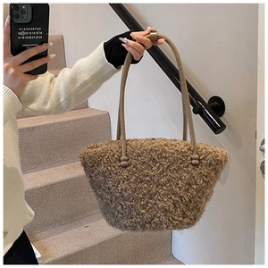 Detail of plush brown shearling handbag with slender leather handle in a minimalist style