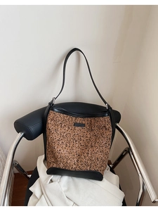 Detailed close-up of leopard print bucket bag with black PU leather trim and logo patch