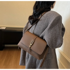 Close-up of brown litchi pattern leather shoulder bag with champagne gold clasp