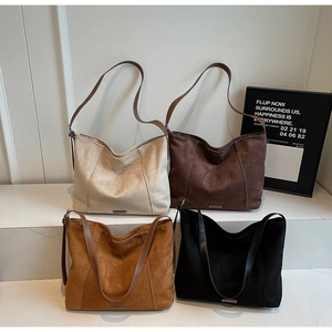 Collection of large suede tote bags in four neutral colors on a marble display