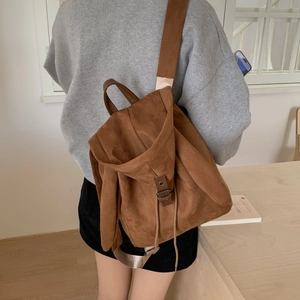 Detail of a brown matte suede backpack featuring wide straps and drawstring closure