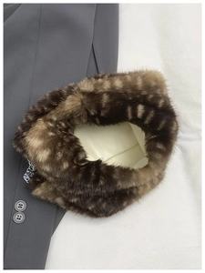 Close-up of the plush faux mink texture and silver chain strap on a brown striped tote bag