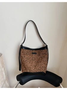 Detailed shot of leopard print bucket bag with black leather trim on a black chair