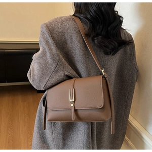 Brown litchi texture leather shoulder bag with golden buckle on a wool coat