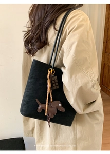 Black matte tote bag detail with dachshund dog charm worn on a beige trench coat