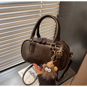Detail of coffee brown leather Boston bag with dual zippers and plush charm