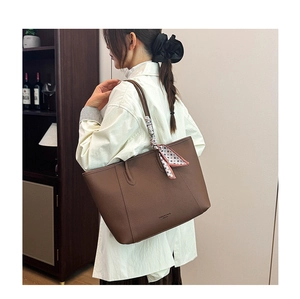 Brown leather tote bag with silk scarf detail shown in an elegant lifestyle setting