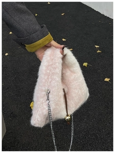 Détail du sac à bandoulière rose en fausse fourrure avec chaîne et clochette dorée