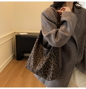 Detail of large leopard print tote bag with brown shoulder strap and metal buckle
