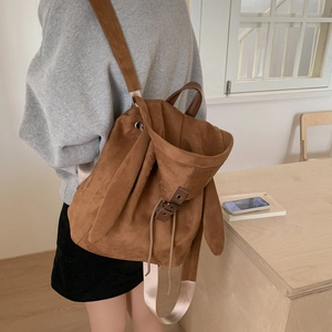 Brown faux suede backpack with cute rabbit ear design worn by model in a cozy room