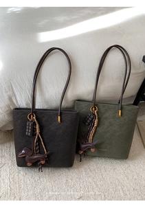 Detail view of dark brown and olive green frosted leather tote bags with cute dachshund charms