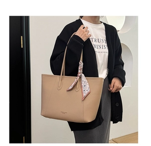 Detail showing the lychee leather texture and silk scarf handle of the khaki tote bag