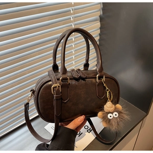 Detailed view of dark brown retro Boston bag with plush doll charm and gold hardware