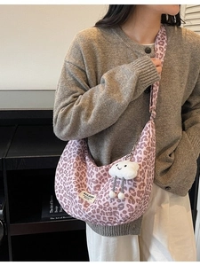 Pink leopard print hobo tote bag with cloud charm pendant on a casual grey sweater model