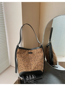 Detail of leopard print bucket bag with black leather trim and logo on textured background