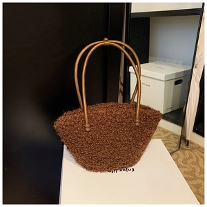 Detail of a brown plush bucket bag with leather handles and decorative beads