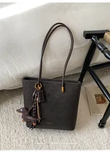 Macro detail of dark brown retro tote bag with lychee texture and playful charms