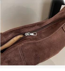 Detail of smooth metal zipper and white contrast stitching on coffee suede tote bag