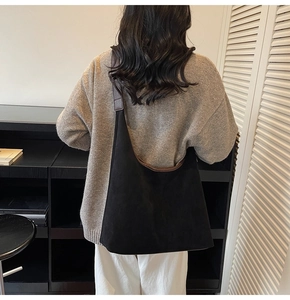Detailed back view of a large black matte tote bag with brown leather straps worn by model