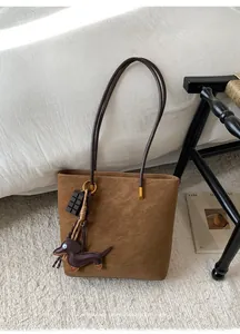 Brown suede tote bag with unique dachshund and chocolate charms on a white carpet
