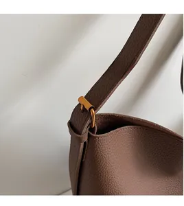 Détail de la bandoulière réglable et boucle en métal doré sur sac en cuir marron