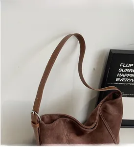 Detail of adjustable leather strap with silver buckle and white stitching on brown bag
