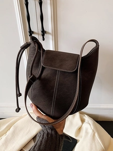 Brown bucket shoulder bag with white contrast stitching and adjustable strap