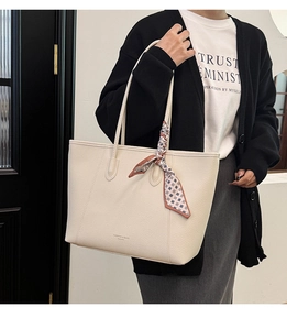 Detail of off-white lychee grain leather tote bag with printed silk scarf and long straps