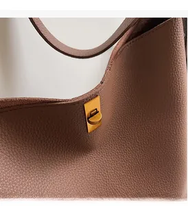 Détail du sac cabas en cuir marron grainé avec fermoir rotatif en métal doré poli