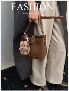Close-up of brown matte leather bucket bag with U-shaped stitching and bear charm