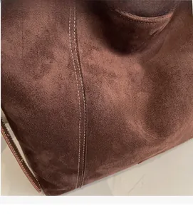 Close-up of brown suede tote bag featuring detailed white contrast stitching and soft texture