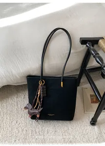 Detail of black suede tote bag with golden hardware and creative dachshund pendant