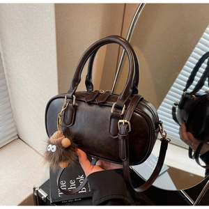 Detail of dark brown Boston bag with smooth faux leather texture and plush monster charm