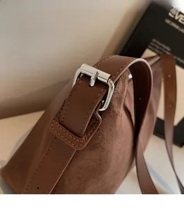 Détail de la boucle en métal argenté et textures de cuir sur le sac à main marron