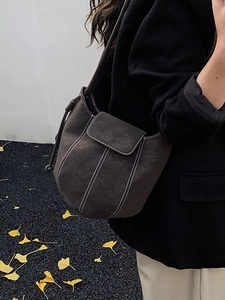Minimalist dark brown suede bucket bag with white contrast stitching and shoulder strap