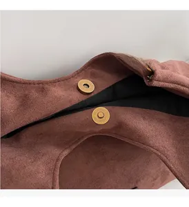 Détails des fermoirs magnétiques dorés sur un sac fourre-tout en daim marron foncé