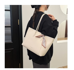 Close-up of cream tote bag with litchi texture and silk scarf detail on model